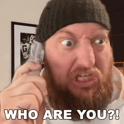 A Man With A Beard Is Making A Funny Face While Talking On A Cell Phone And Says Who Are You ? GIF