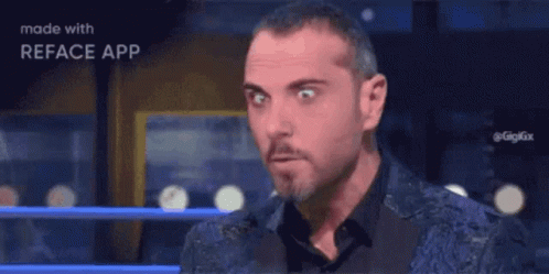 A Man With A Beard Is Making A Funny Face While Wearing A Blue Jacket And Black Shirt . GIF