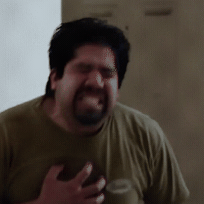 A Man With A Beard Is Making A Funny Face While Wearing A Green Shirt GIF