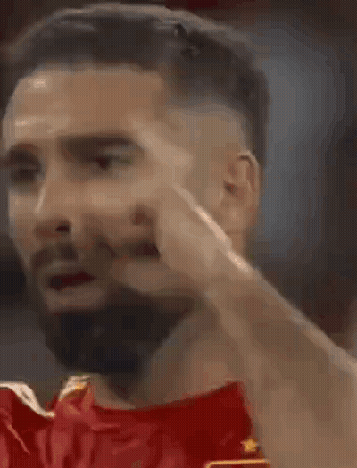 A Man With A Beard Is Making A Funny Face While Wearing A Red Shirt . GIF