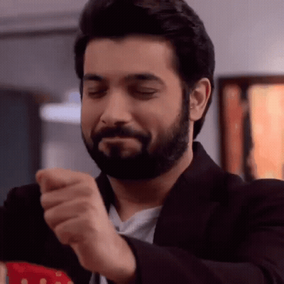 A Man With A Beard Is Making A Funny Face While Wearing A Suit And A Tie . GIF