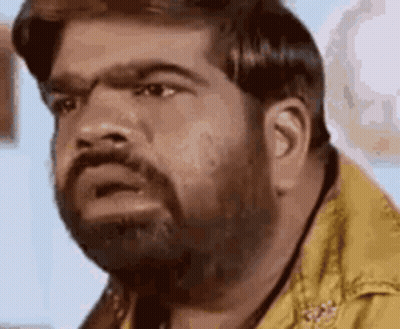 A Man With A Beard Is Making A Funny Face While Wearing A Yellow Shirt . GIF