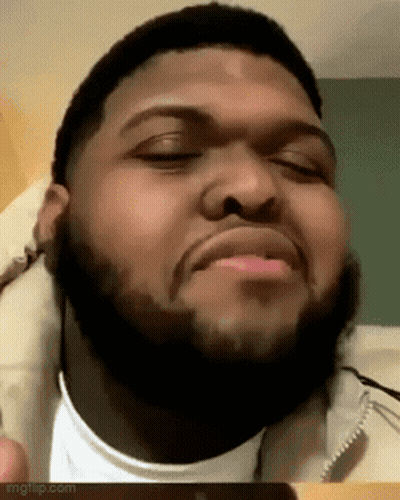 A Man With A Beard Is Making A Funny Face With His Eyes Closed And His Mouth Open . GIF