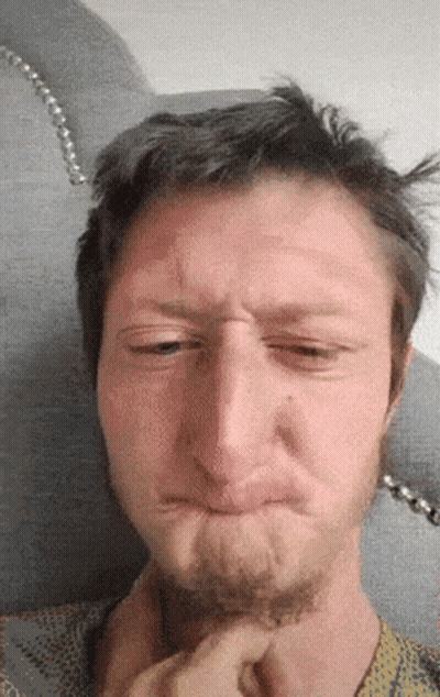 A Man With A Beard Is Making A Funny Face With His Eyes Closed GIF