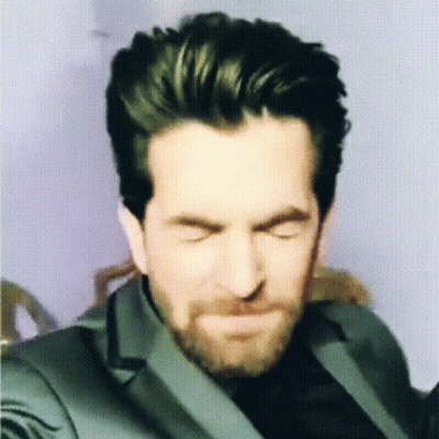 A Man With A Beard Is Making A Funny Face With His Eyes Closed GIF