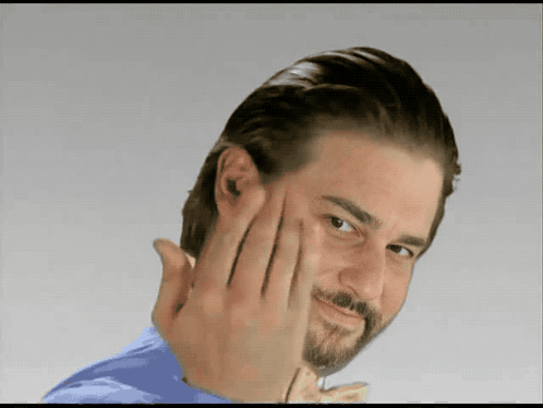 A Man With A Beard Is Making A Funny Face With His Hand GIF