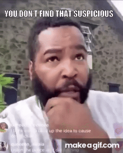 A Man With A Beard Is Making A Funny Face With His Hand On His Chin And A Stone Wall In The Background . GIF