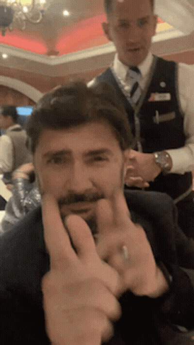 A Man With A Beard Is Making A Peace Sign With His Fingers GIF