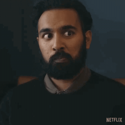 A Man With A Beard Is Making A Surprised Face In A Dark Room . GIF
