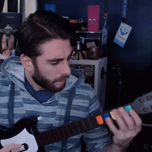 A Man With A Beard Is Playing A Guitar In Front Of A Sign That Says ' Evo ' On It GIF