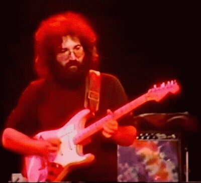 A Man With A Beard Is Playing A Guitar On Stage GIF