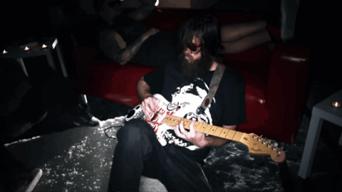 A Man With A Beard Is Playing A Guitar With A Sticker On It That Says ' Nirvana ' On It GIF