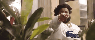 A Man With A Beard Is Pointing At The Camera While Standing In Front Of A Window . GIF