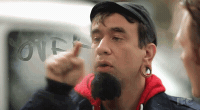 A Man With A Beard Is Pointing At The Word Over Written On A Window GIF