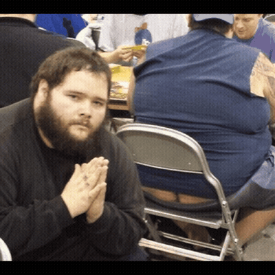 A Man With A Beard Is Praying While Sitting In A Chair GIF