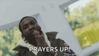 A Man With A Beard Is Praying With His Hands Folded In Front Of His Face . GIF