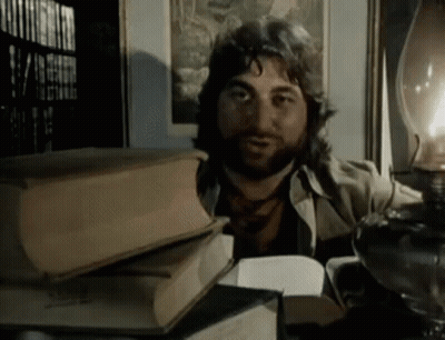 A Man With A Beard Is Reading A Book GIF