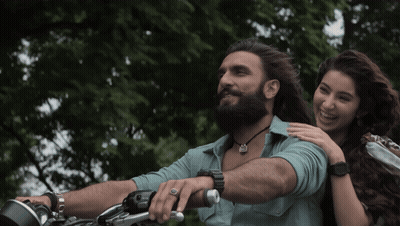 A Man With A Beard Is Riding A Motorcycle While A Woman Holds His Arm GIF