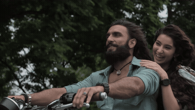 A Man With A Beard Is Riding A Motorcycle While A Woman Holds His Arm GIF