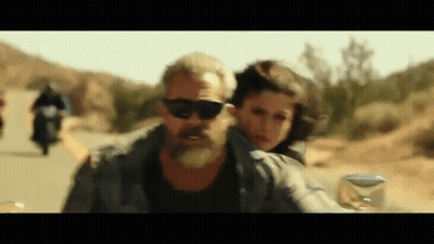A Man With A Beard Is Riding A Motorcycle With A Woman On The Back . GIF
