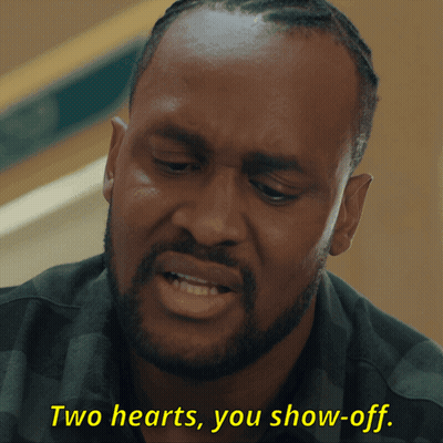 A Man With A Beard Is Saying Two Hearts You Show Off GIF