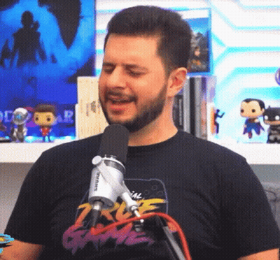 A Man With A Beard Is Singing Into A Microphone While Wearing A T-Shirt That Says 2K Game GIF