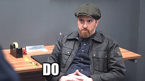 A Man With A Beard Is Sitting At A Desk With The Word Do Written On It GIF