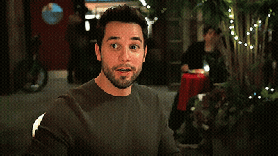 A Man With A Beard Is Sitting At A Table In A Dark Room GIF