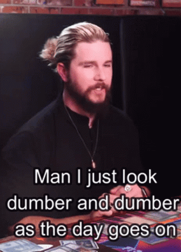 A Man With A Beard Is Sitting At A Table With A Caption That Reads Man I Just Look Dumber GIF