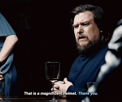 A Man With A Beard Is Sitting At A Table With A Glass Of Wine And Says That Is A Magnificent Helmet Thank You GIF