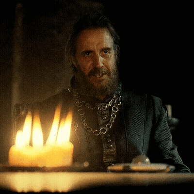 A Man With A Beard Is Sitting At A Table With A Lit Candle In Front Of Him GIF