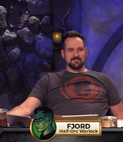 A Man With A Beard Is Sitting At A Table With A Name Tag That Says Fjord Half-Orc Warlock GIF