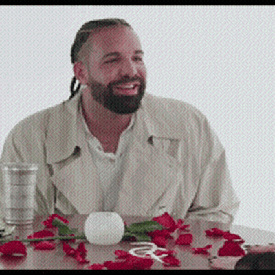 a man with a beard is sitting at a table with red roses and a glass of water