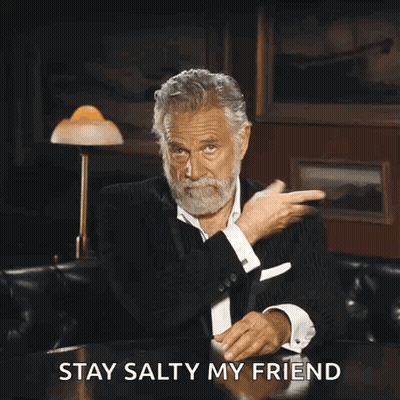 A Man With A Beard Is Sitting At A Table With The Words " Stay Salty My Friend " Written Below Him GIF