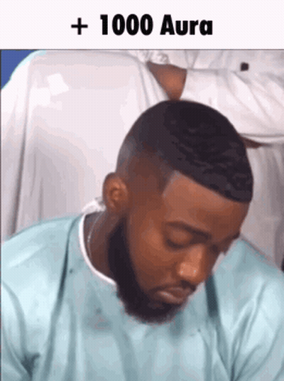 A Man With A Beard Is Sitting Down With His Eyes Closed And A Caption That Says + 1000 Aura . GIF