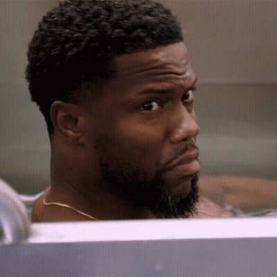 A Man With A Beard Is Sitting In A Bathtub Looking At The Camera GIF