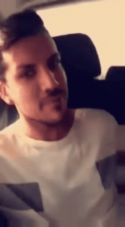 A Man With A Beard Is Sitting In A Car . GIF