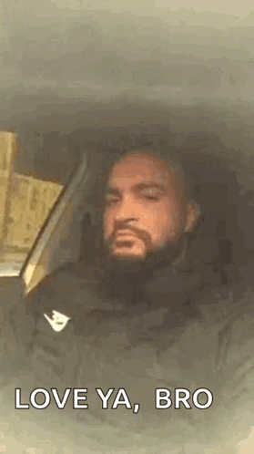 A Man With A Beard Is Sitting In A Car With His Eyes Closed And The Words `` Love Ya , Bro '' . GIF