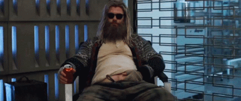 A Man With A Beard Is Sitting In A Chair And Holding A Can Of Soda GIF