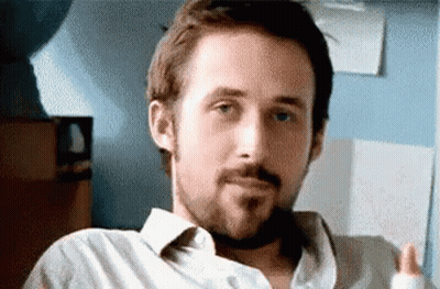 A Man With A Beard Is Sitting In A Chair And Making A Face . GIF