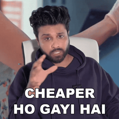 A Man With A Beard Is Sitting In A Chair And Says " Cheaper Ho Gayi Hai " GIF