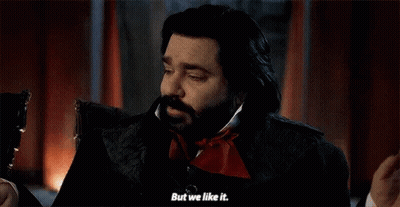 A Man With A Beard Is Sitting In A Chair And Talking To Another Man . GIF
