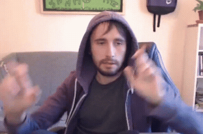 A Man With A Beard Is Sitting In A Chair Wearing A Hoodie And Making A Funny Face . GIF