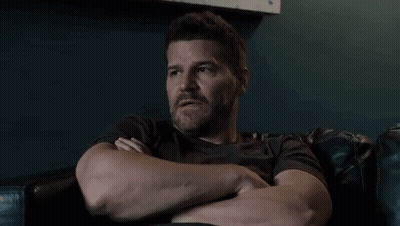 A Man With A Beard Is Sitting In A Chair With His Arms Crossed GIF