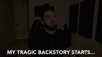 A Man With A Beard Is Sitting In A Dark Room With The Words My Tragic Backstory Starts Behind Him GIF