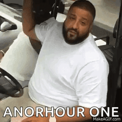A Man With A Beard Is Sitting In A Golf Cart With The Words `` An Hour One '' Written On It . GIF