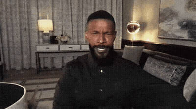 A Man With A Beard Is Sitting In A Living Room GIF