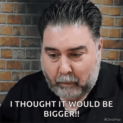 A Man With A Beard Is Sitting In Front Of A Brick Wall . GIF
