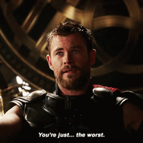 A Man With A Beard Is Sitting In Front Of A Clock And Says " You 'Re Just The Worst " GIF