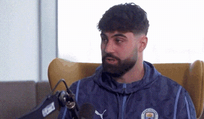 A Man With A Beard Is Sitting In Front Of A Microphone . GIF